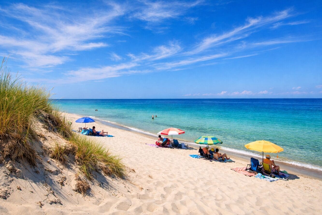 () wide-angle photograph of Sandbanks Provincial Park beach at midday, white sand stretching into clear shallow turquoise